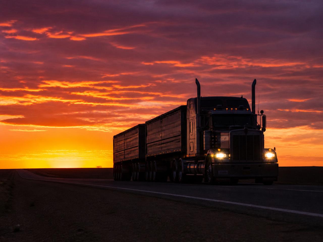Silhouette of a semi-truck against a dramatic sunset