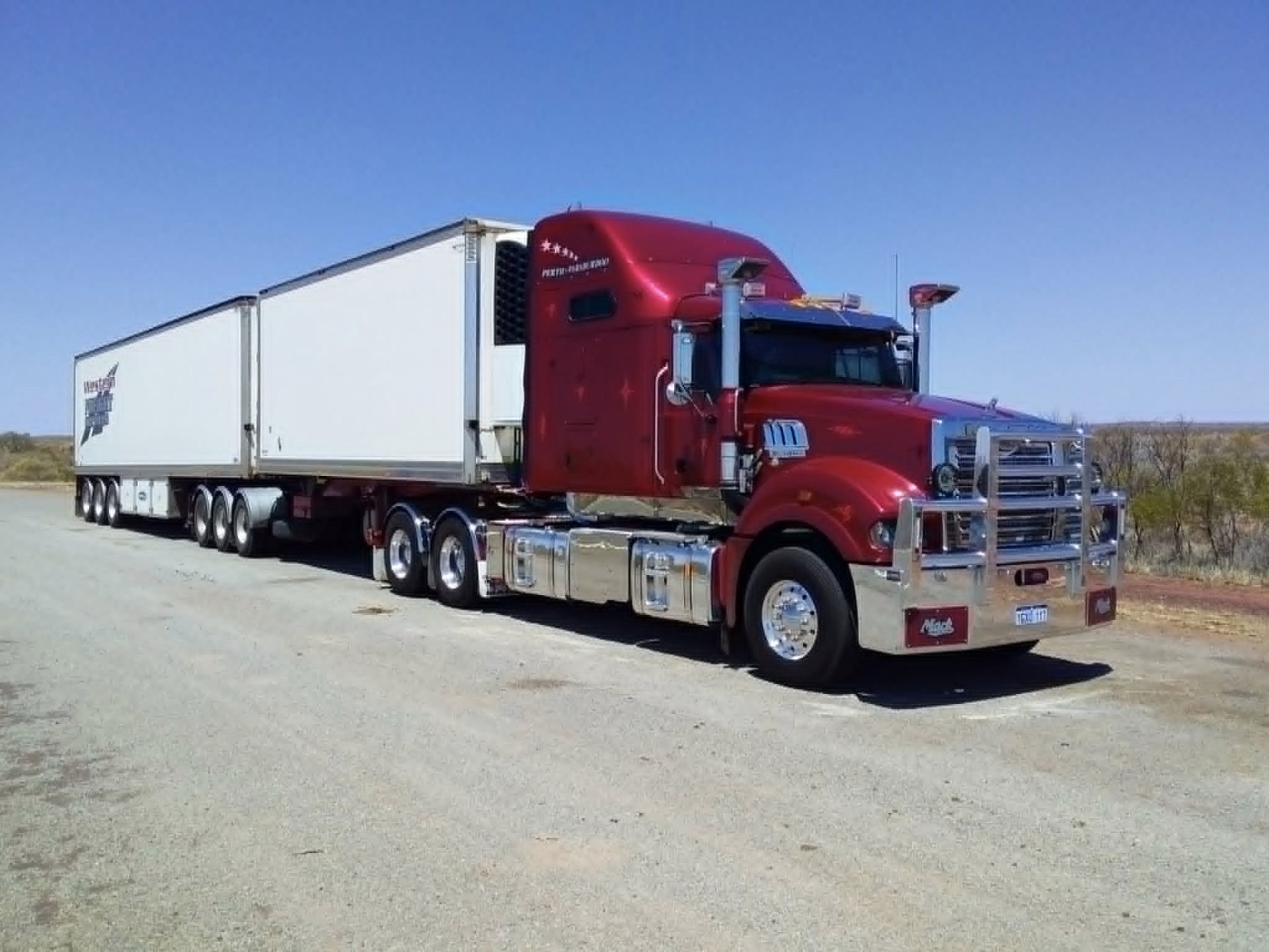Deep red prime mover with WFS refrigerated B-double on a Pilbara roadside